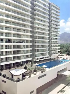 a large building with a swimming pool in front of it at Apartaestudio con hotel y playa in Santa Marta