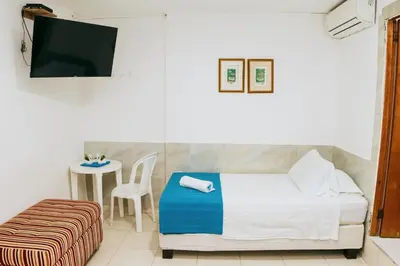 a bedroom with a bed and a table with a chair at Hotel Ibatama in Cartagena de Indias