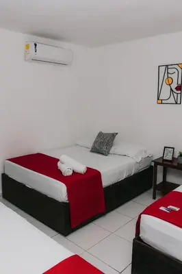 a bedroom with a bed with red and white sheets at Hotel Ibatama in Cartagena de Indias