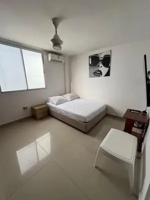 a bedroom with a bed and a table and window at Acogedor espacio familiar in Cartagena de Indias