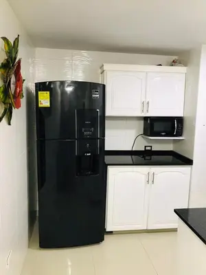 a black refrigerator in a kitchen with white cabinets at Acogedor espacio familiar in Cartagena de Indias