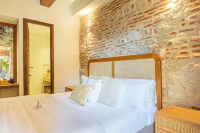 a bedroom with a white bed with a brick wall at Casa Emilia - Luxury Villa in the Historic Center in Cartagena de Indias