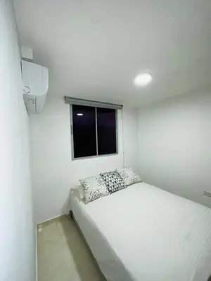 a small white room with a bed and a window at cool and quiet apartment in front of the urban forest in Barranquilla