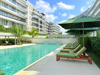 a row of lounge chairs and an umbrella next to a swimming pool at Magnificent Apartment - Beach - Jacuzzis! in Cartagena de Indias