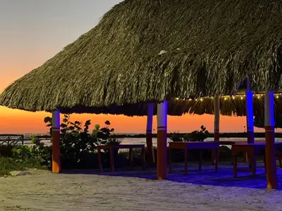 a table and chairs under a straw umbrella on the beach at Habitacion Ely Johana in Coveñas