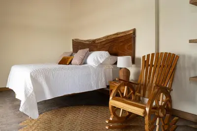a bedroom with a bed with a wooden headboard and a chair at Casa Barú in Baru