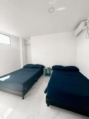 two beds in a white room with blue sheets at Maru apartamentos #6 in Cartagena de Indias