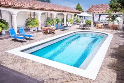 a swimming pool with blue chairs and a house at Hotel Santorini Casablanca Resort in Santa Marta