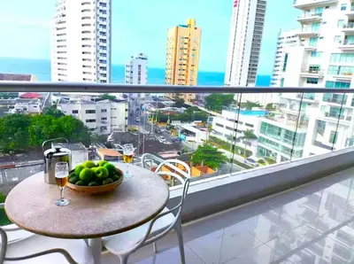 a table with a bowl of fruit and wine glasses on a balcony at Incredible apartment in Cartagena a few meters from the Sea in Cartagena de Indias