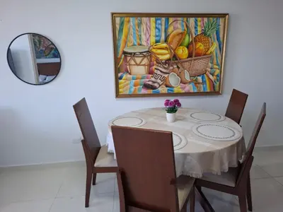 a dining room with a table with chairs and a painting at Ocean View Apartment - Soho Playa Mendoza in Tubará