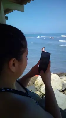 a woman taking a picture of the ocean with her cell phone at Casa Lagomar in Pradomar