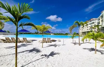 a beach at the resort with chairs and palm trees at Apartamentos Baia Kristal - Escapada a Cartagena in Cartagena de Indias