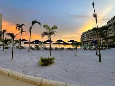 a beach with chairs and umbrellas and palm trees at Apartamentos Baia Kristal - Escapada a Cartagena in Cartagena de Indias