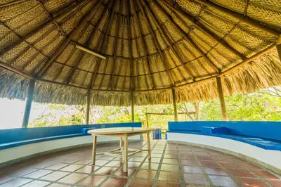 a table in a straw roofed hut with a table at Paraíso By Elemnt Rentals in Santa Marta