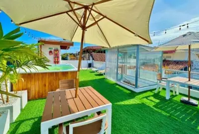 a patio with a wooden bench with an umbrella at Hotel Capsula CAPS Cartagena in Cartagena de Indias