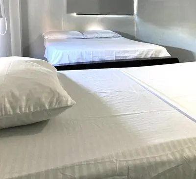 two beds in a room with white sheets and pillows at Hotel Tres Estrellas Fundacion in Fundación