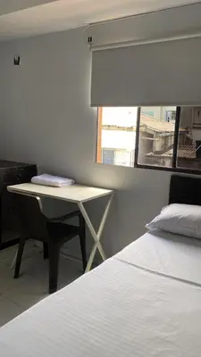 a bedroom with a bed and a desk and a window at Hotel Tres Estrellas Fundacion in Fundación