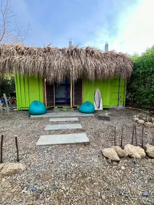 a green hut with a straw roof and some rocks at Riders Shared Room en Mojarra Beach in Salina de Rey