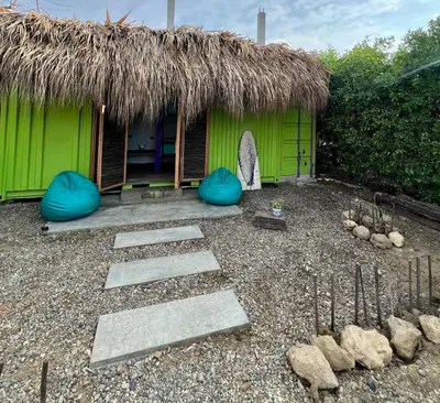 a green hut with a thatched roof and some rocks at Riders Shared Room en Mojarra Beach in Salina de Rey