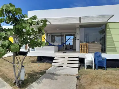 a house on the beach with two chairs at Marina Puerto Velero Cabaña in Tubará