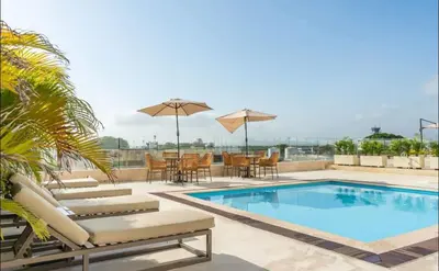 a swimming pool with chairs and tables and umbrellas at Cartagena Beach exclusive & Resort in Cartagena de Indias