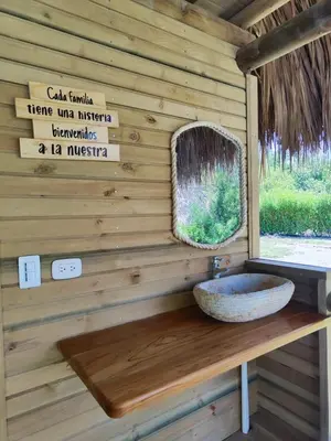 a bathroom with a stone sink on a wooden wall at Cabaña de playa 6 personas con cocina y kiosko privado in Moñitos