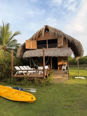 a hut with a yellow surfboard in front of it at Cabaña de playa 6 personas con cocina y kiosko privado in Moñitos