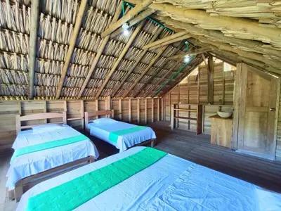a room with two beds in a wooden building at Cabaña de playa 6 personas con cocina y kiosko privado in Moñitos