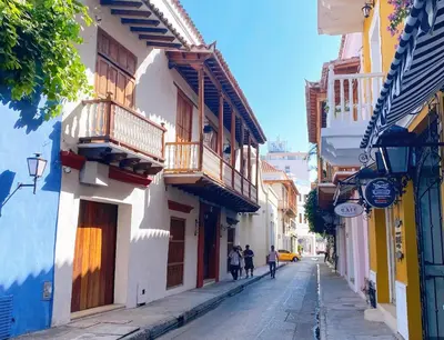 a narrow street with people walking down the street at Experience the magic of the Calle de las Damas historic center in Cartagena de Indias