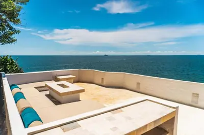 an outdoor seating area with the ocean in the background at Paradise Private Kaimari Ocean Villa in Cartagena de Indias