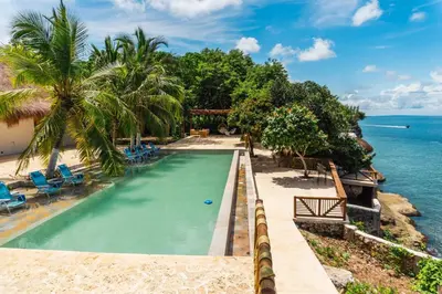 an infinity pool with palm trees and the ocean at Paradise Private Kaimari Ocean Villa in Cartagena de Indias