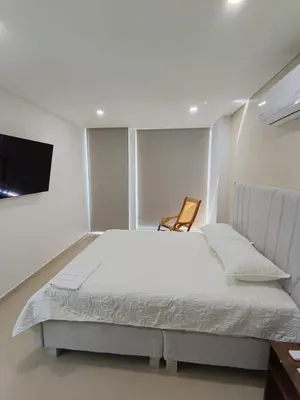 a bedroom with a large bed and a chair at 612 Beautiful Apartment Near the Walled City in Cartagena de Indias
