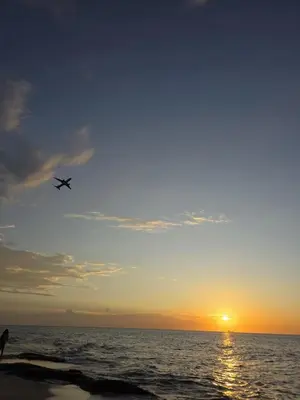 an airplane flying over the ocean at sunset at Apartamento cerca a la playa y al aeropuerto in Santa Marta