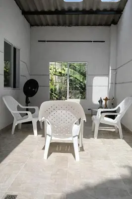 a room with white chairs and a table and a window at Apartamento cerca a la playa y al aeropuerto in Santa Marta