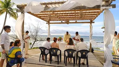 a group of people sitting at a table at a wedding on the beach at Sarao Mar in Moñitos