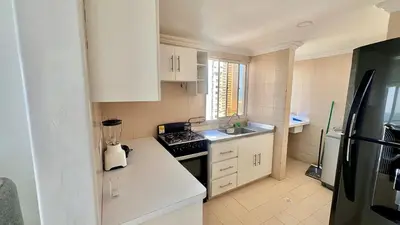 a small kitchen with white cabinets and a black stove at Apartamento Marina del Rey 1101 in Cartagena de Indias