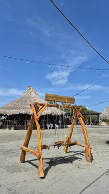 a wooden bench on a beach with a hut at Apto 411 puerto velero in Tubará