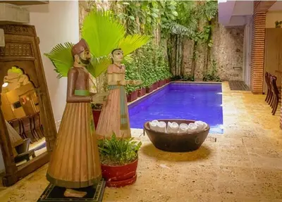 a swimming pool with two figurines next to a tub at Casa Del Hobo in Cartagena de Indias