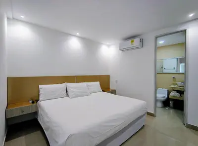a bedroom with a white bed and a bathroom at Apartasuites Amoblados Norte de Barranquilla-Atlantis Suites in Barranquilla