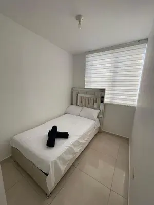 a white bedroom with a bed with a black hat on it at El encanto de Cartagena in Cartagena de Indias