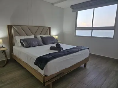 a bedroom with a large bed with a large window at Brand New Perfectly Located 2bedroom in CieloMar in Cartagena de Indias