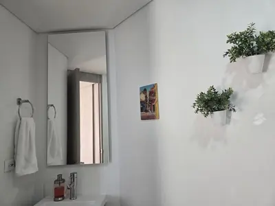 a white bathroom with a mirror and a sink at Brand New Perfectly Located 2bedroom in CieloMar in Cartagena de Indias