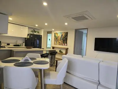a living room with a table and chairs and a kitchen at Brand New Perfectly Located 2bedroom in CieloMar in Cartagena de Indias