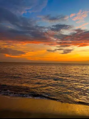 a sunset on the beach with the ocean at Apartamento frente al mar- edificio santa marina in Santa Marta
