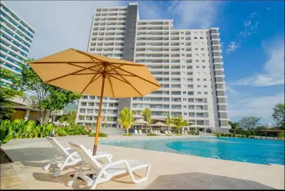 a pool with chairs and an umbrella and a building at Apartamento frente al mar- edificio santa marina in Santa Marta