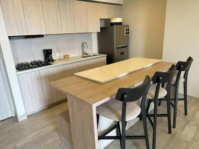 a kitchen with a counter and four chairs at a table at Tu refugio en la playa, moderno cómodo con estilo in Cartagena de Indias