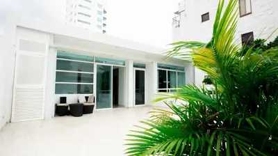 a white house with glass doors and palm trees at MQ CROWN HOUSE CASTIllO in Cartagena de Indias