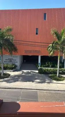 a building with a red roof with palm trees in front at Gisela Wax More Hostel in Cartagena de Indias