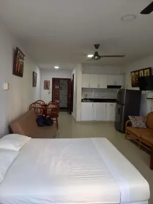 a bedroom with a white bed and a kitchen at Apt Edificio los Delfines Playa in Cartagena de Indias