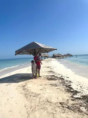 two people standing under an umbrella on a beach at La Dolce Villa! in El Mamey